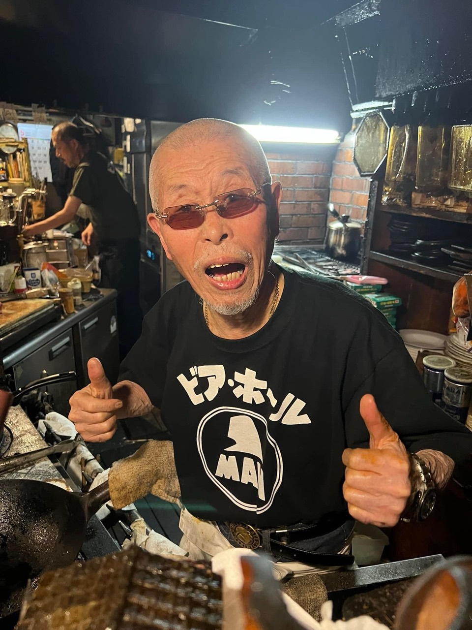 厨房で両手の親指を立てる村田善則マスター