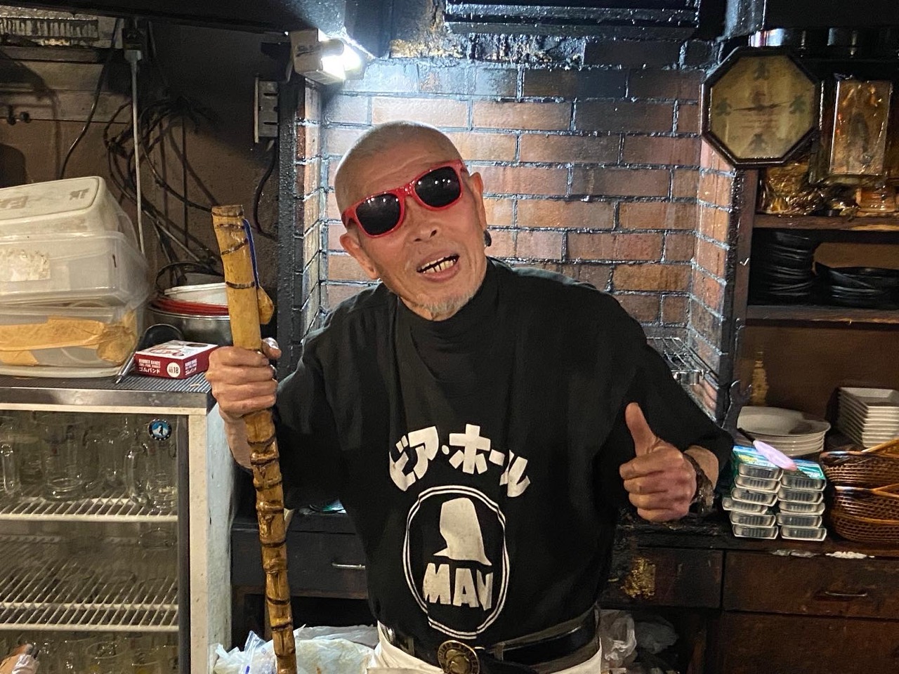 赤いサングラス姿で親指を立てる村田善則マスター