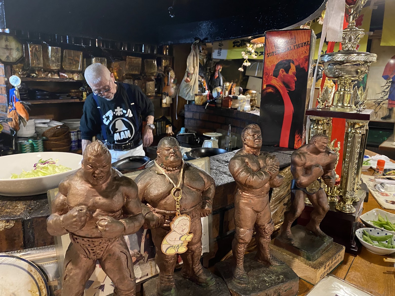 村田マスターと店内に並ぶプロレスラーのブロンズ像