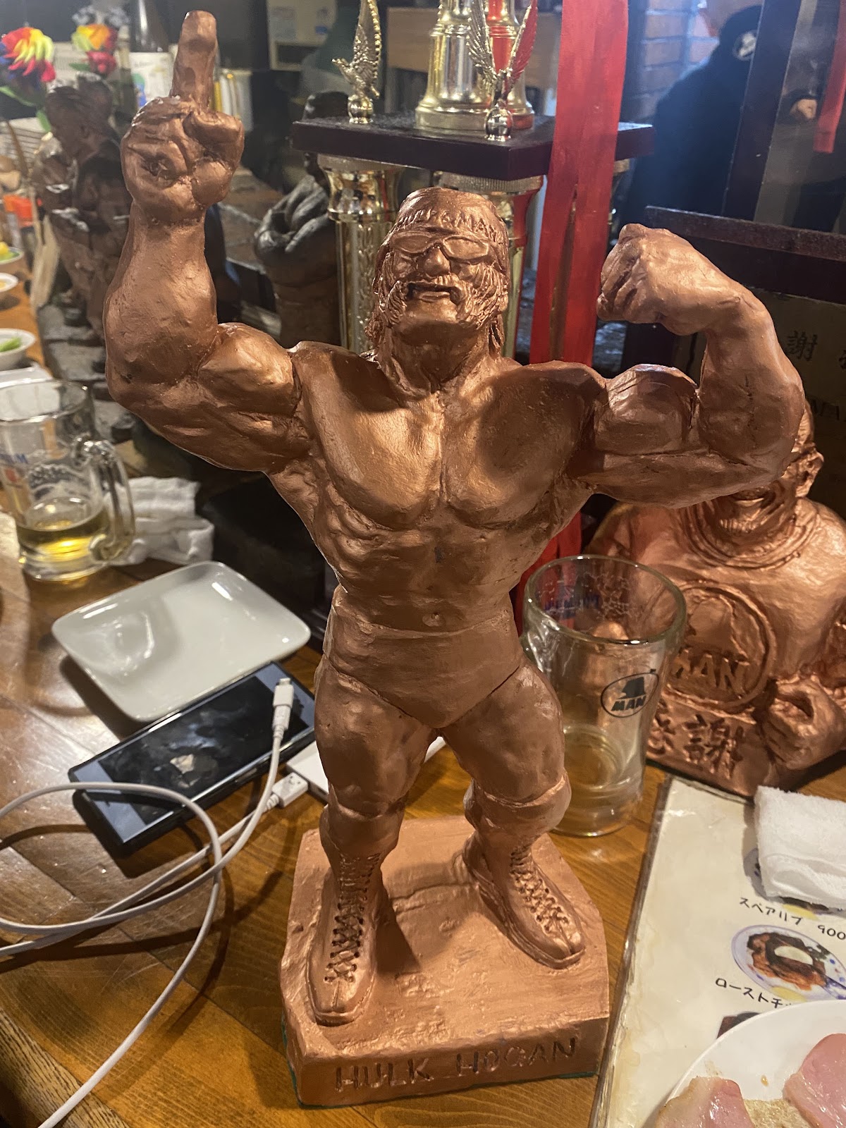 両腕を高く掲げたプロレスラーのブロンズ像