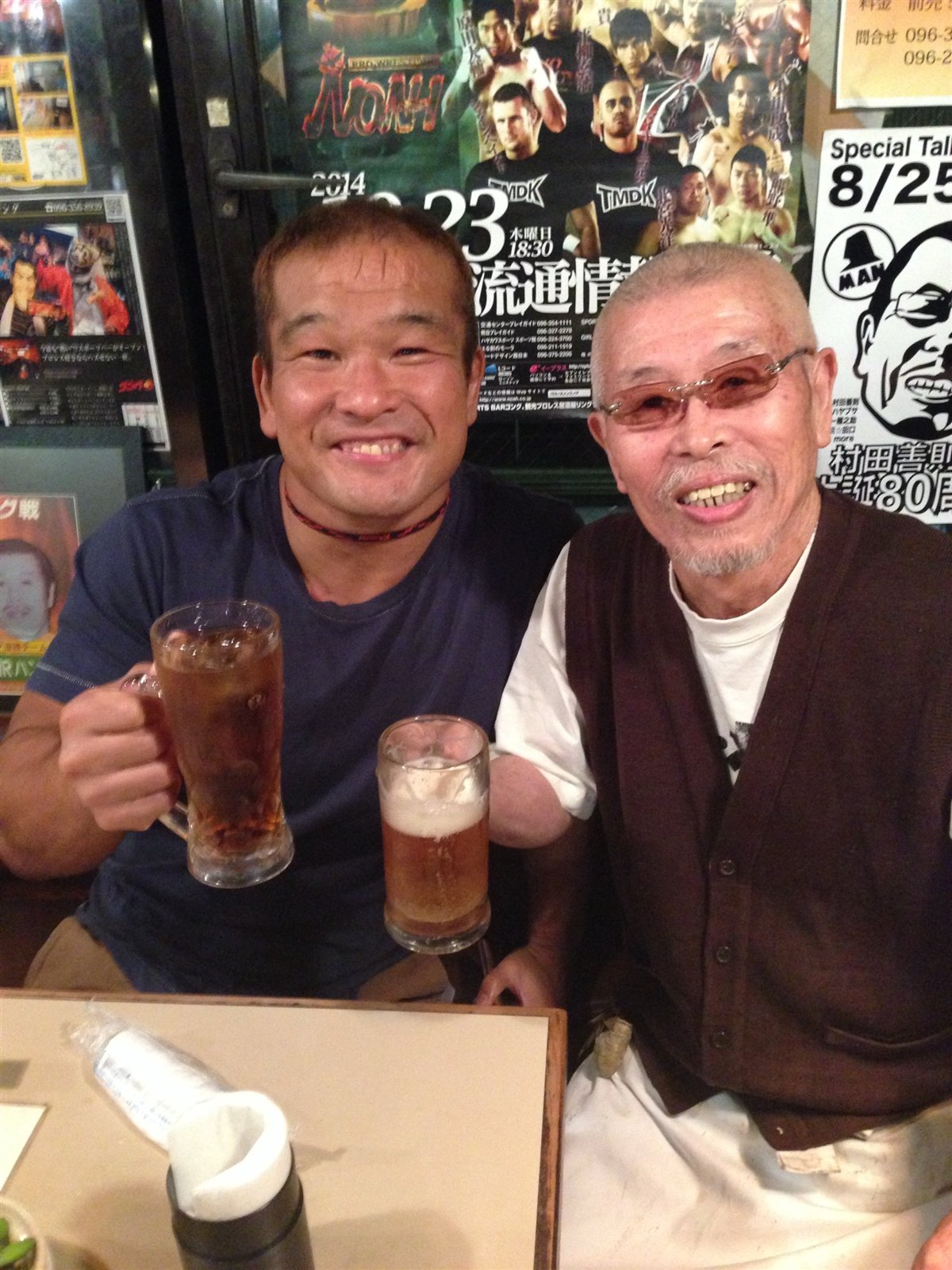 レスラーと村田マスターがグラスを掲げる様子