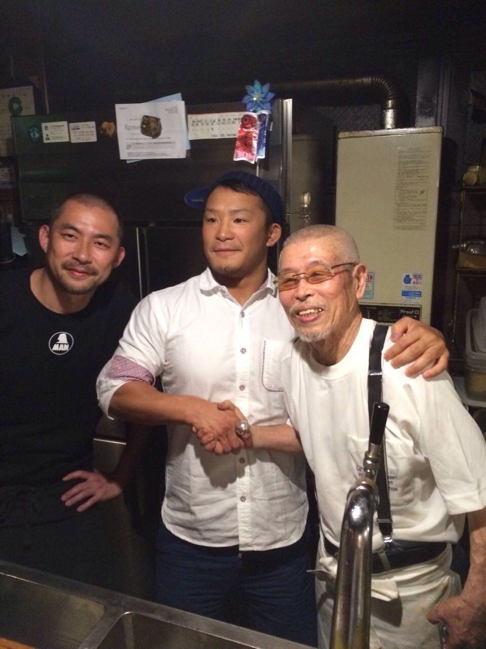 二人のレスラーとカウンターで笑顔を見せる村田マスター