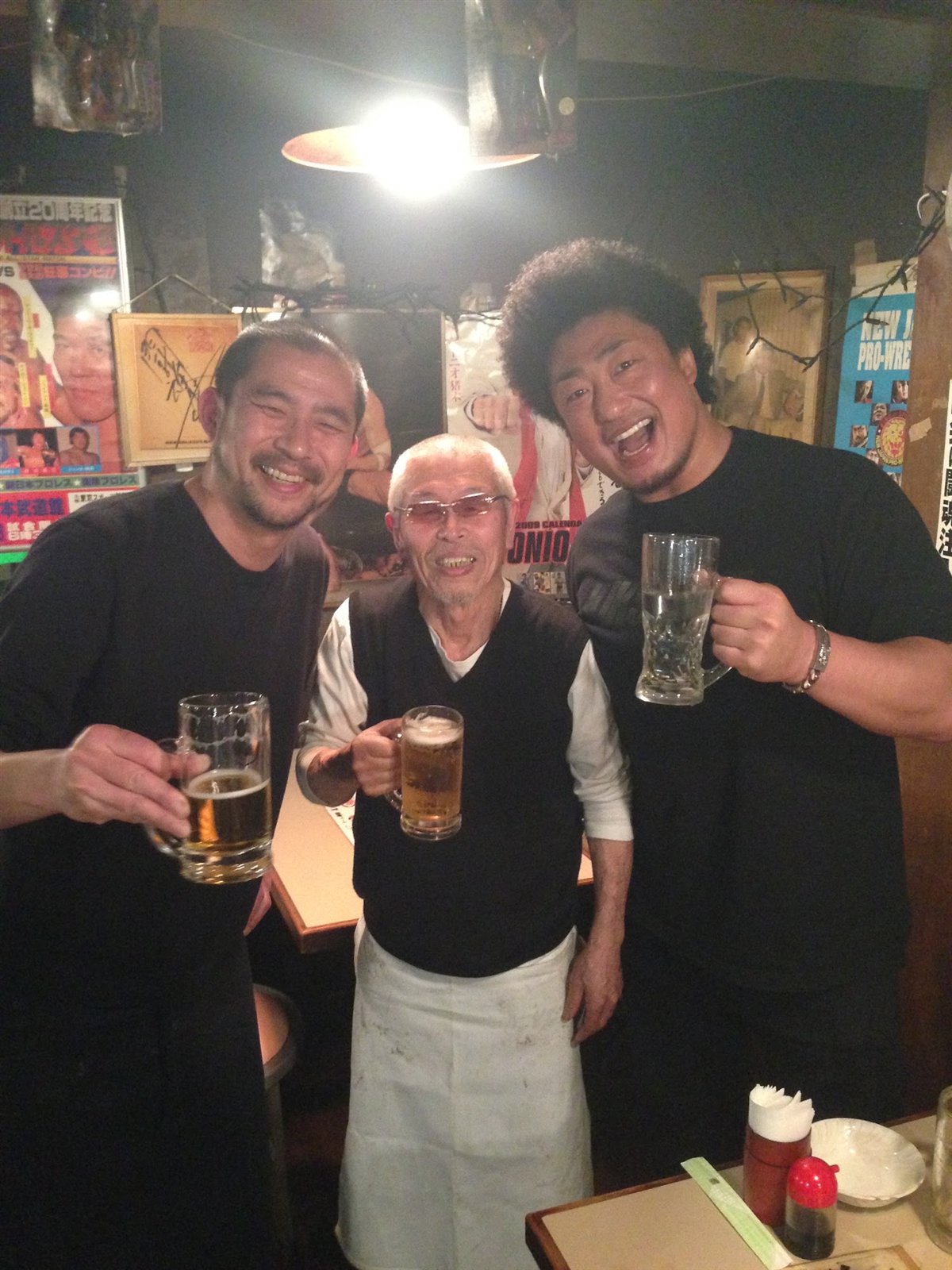 二人のレスラーとグラスを手に笑顔で並ぶ村田マスター